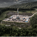 Una vista aérea de una plataforma de perforación petrolera situada en el centro de un denso bosque.